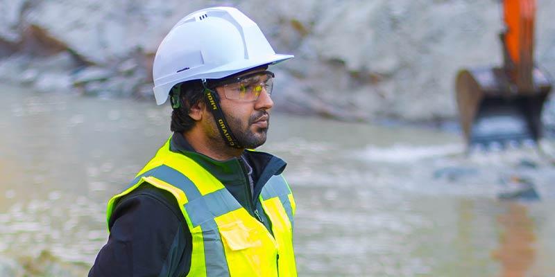 Man at a construction site wearing a high-visibility vest and a hard hat